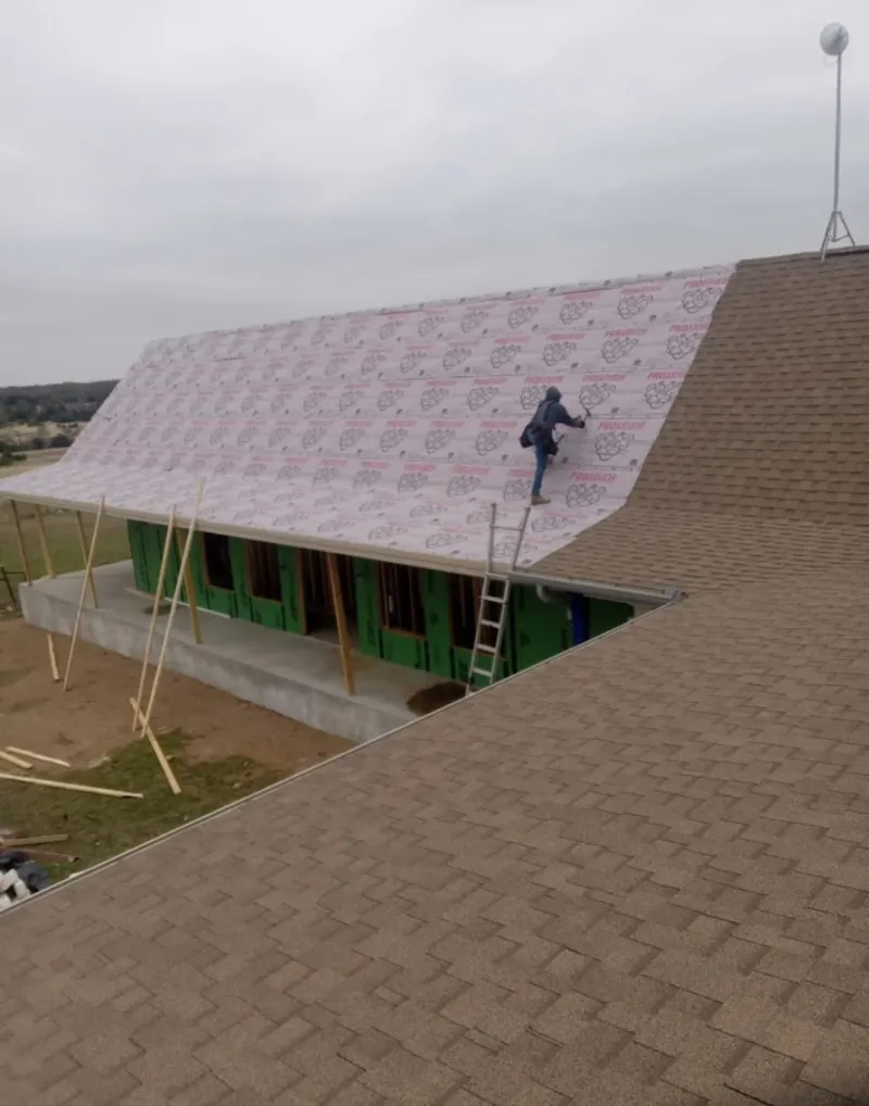 Worker preparing underlayment for a metal roof installation in Brighton